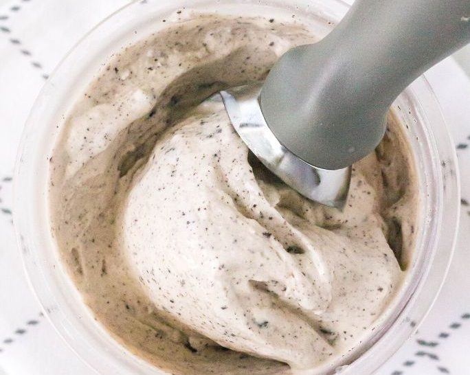 overhead view of a pint of ninja creami cookies and cream ice cream with a scoop in it