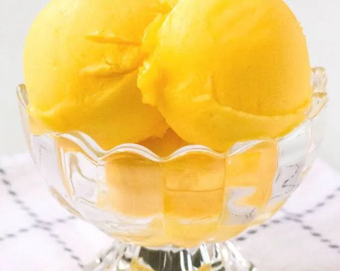 scoops of ninja creami mango sorbet in a glass dish.