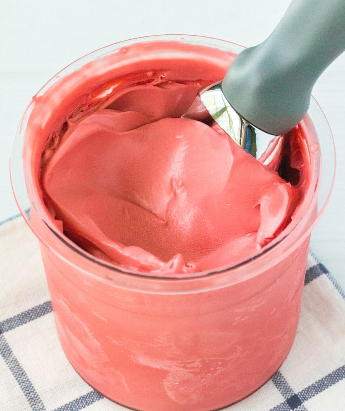 close-up view of Ninja Creami red velvet cake batter ice cream in a pint container, with an ice cream scoop in the top.