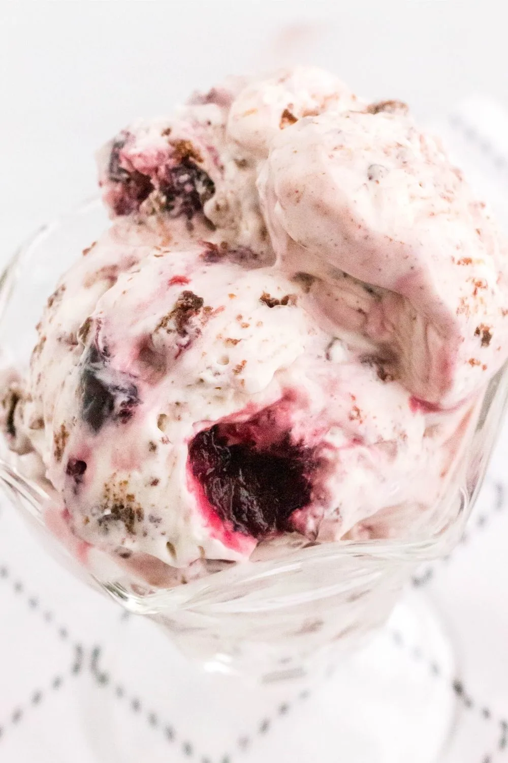 close-up view of two scoops of black forest ice cream in a glass dish. You can see the dark sweet cherries and the chocolate brownie chunks swirled into the ice cream.