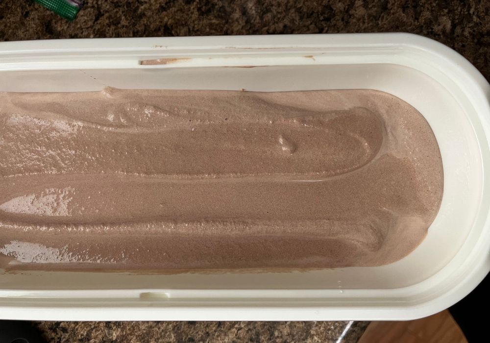 homemade sugar free chocolate ice cream base poured into a white ice cream container before transferring to freezer