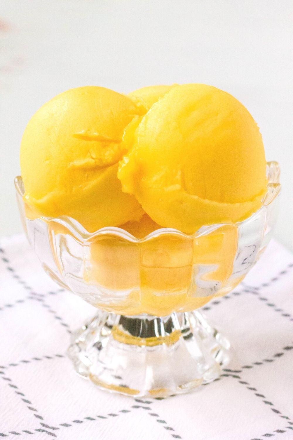 close-up side view of scoops of Ninja Creami mango sorbet served in a glass dish