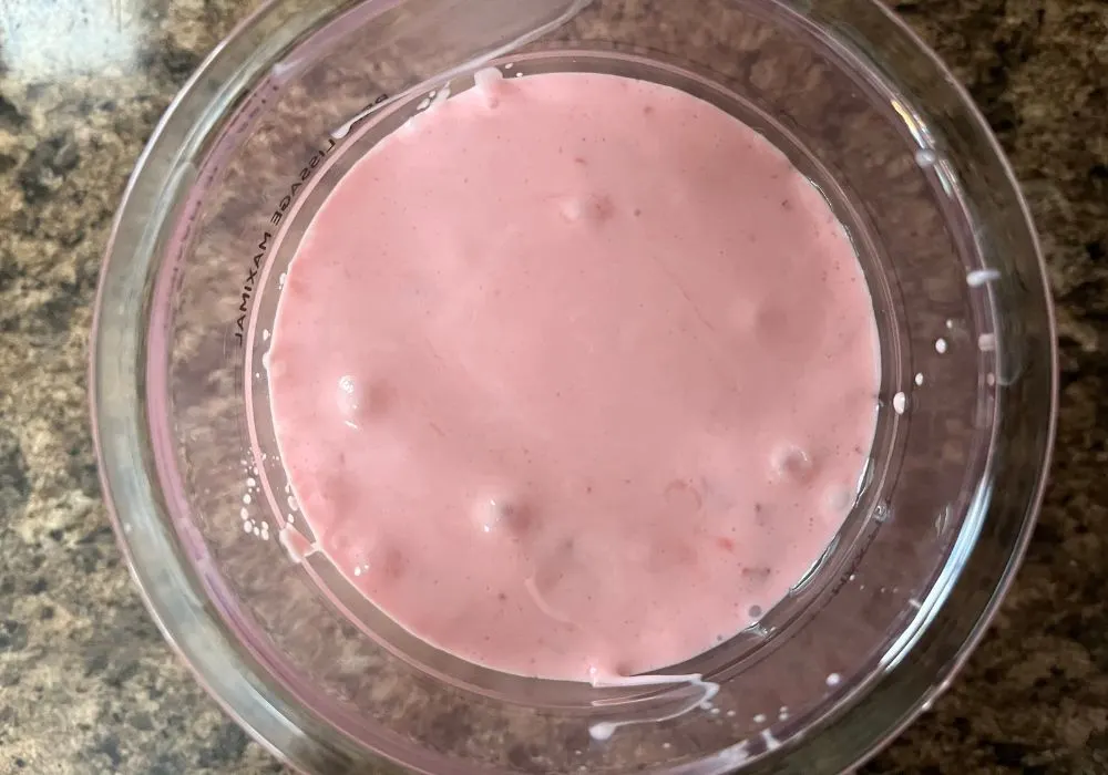 overhead view of a Ninja Creami pint container filled with cherry ice cream base.