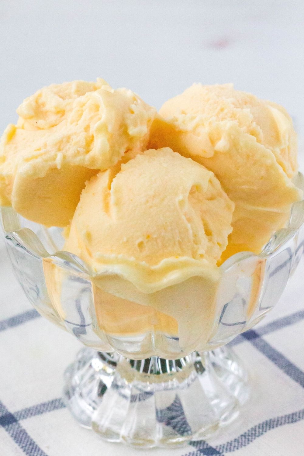 three scoops of Ninja Creami orange sherbet are served in a small glass dessert cup.