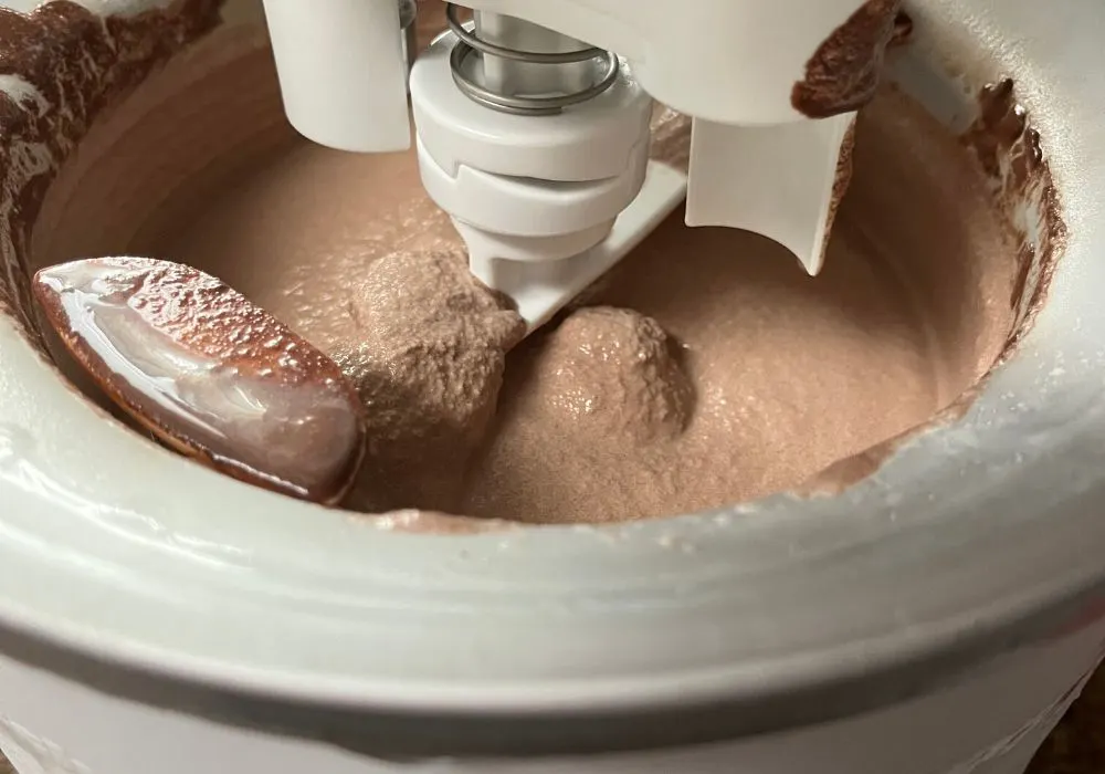 the drum of an ice cream machine is churning the sugar free chocolate ice cream to soft-serve consistency
