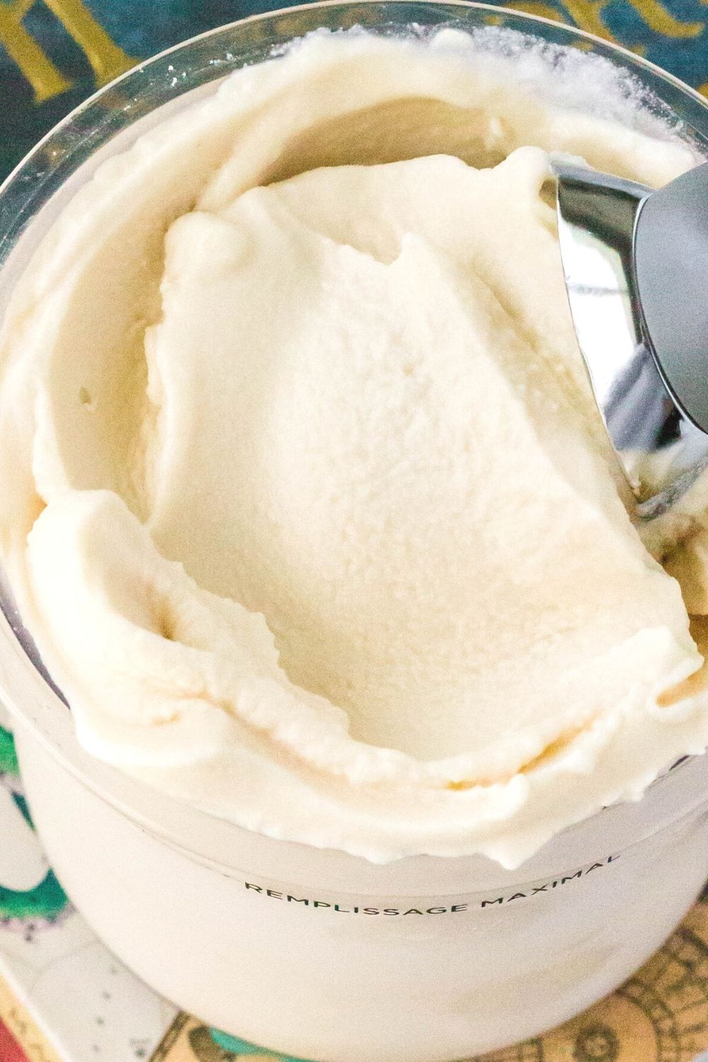 close-up of the top of a Ninja Creami ice cream pint filled with butterbeer ice cream. An ice cream scoop is swirling the top of the ice cream.