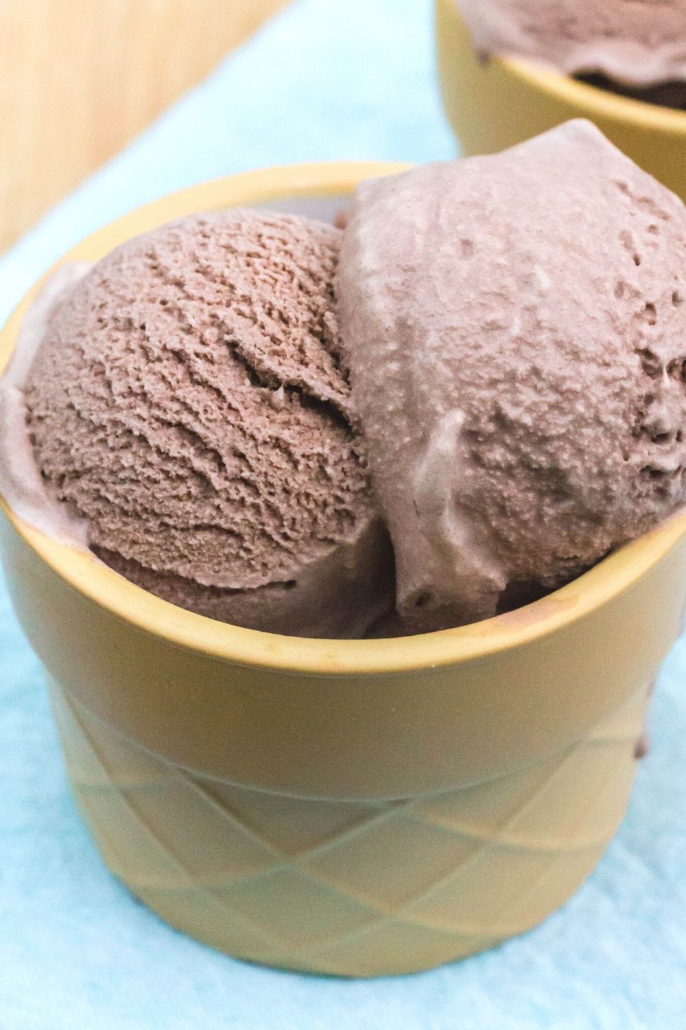 close-up view of two scoops of chocolate ice cream with no added sugar served in a tan dessert cup