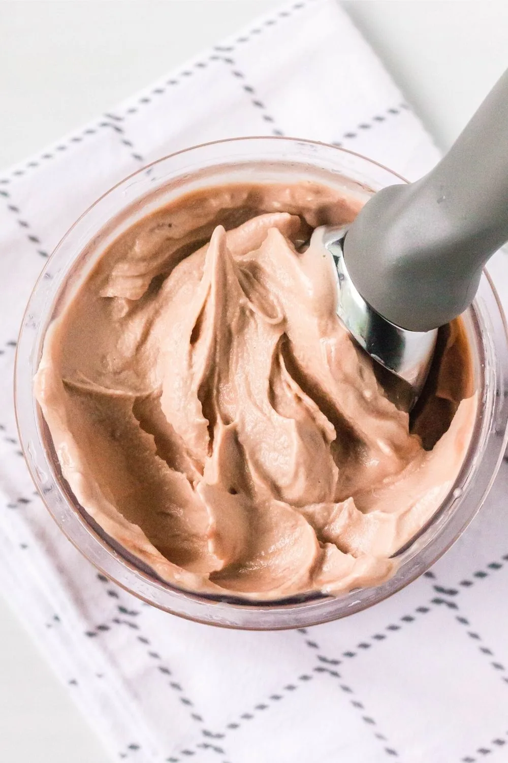 overhead view of a pint of Ninja Creami protein ice cream with an ice cream scoop in it.