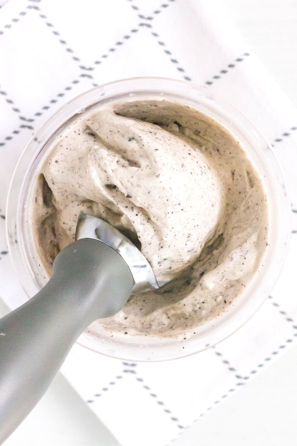overhead view of a ninja creami pint of cookies and cream ice cream, with an ice cream scoop in the pint.