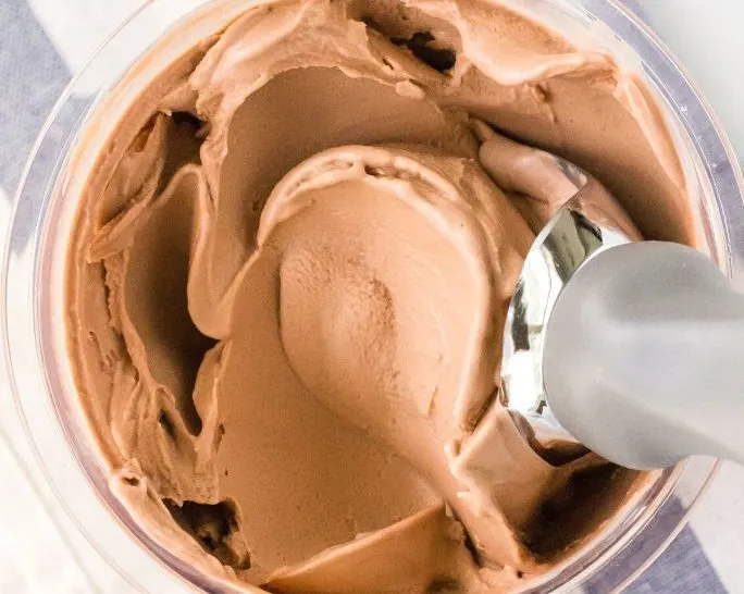 overhead view of a pint of ninja creami dairy free chocolate ice cream with a scoop in it