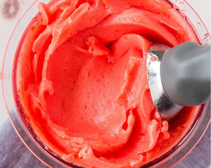 overhead view of Ninja Creami strawberry sorbet in a pint container with an ice cream scoop