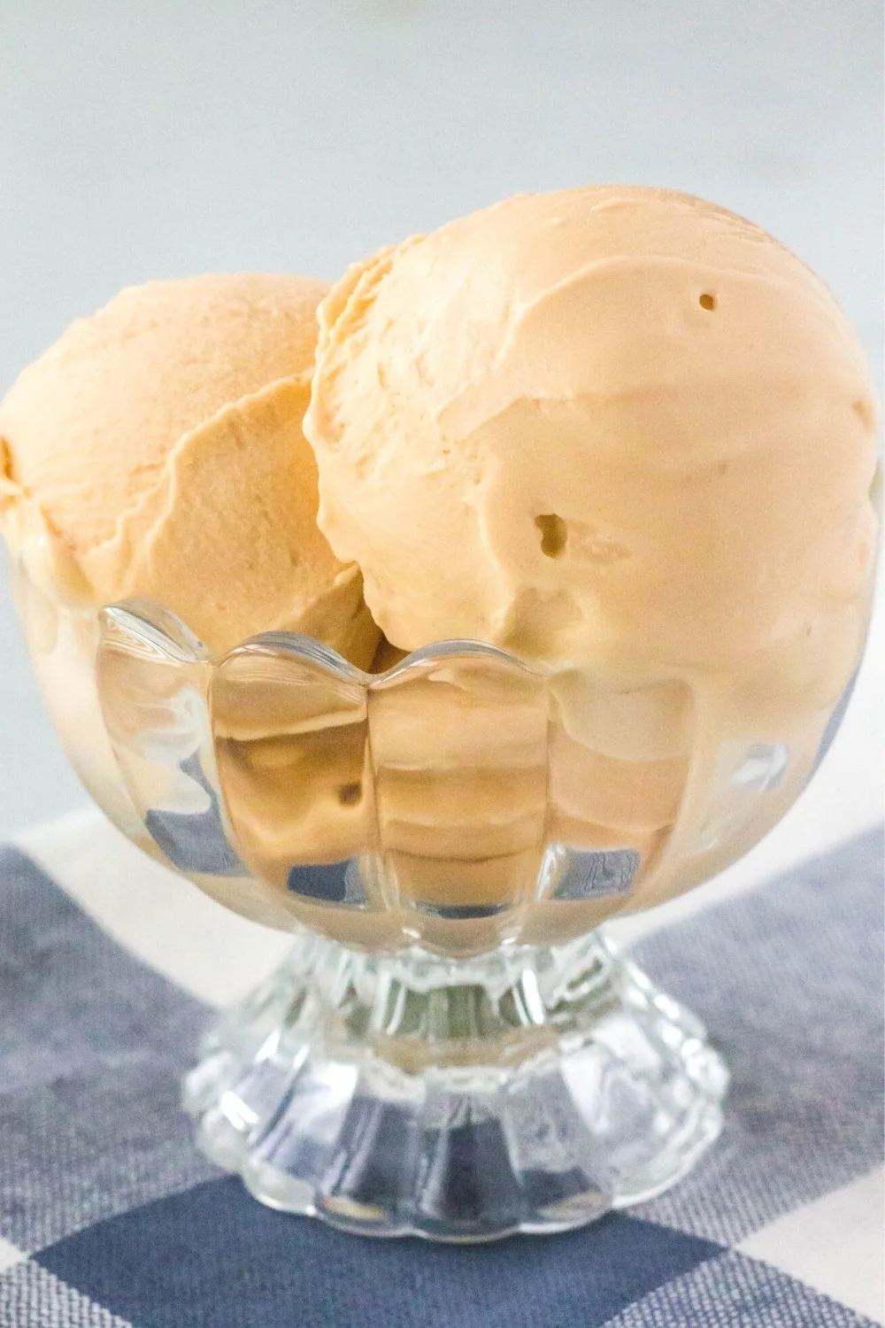 close-up side view of a glass dessert cup filled with scoops of butterscotch ice cream made in the Ninja Creami machine.
