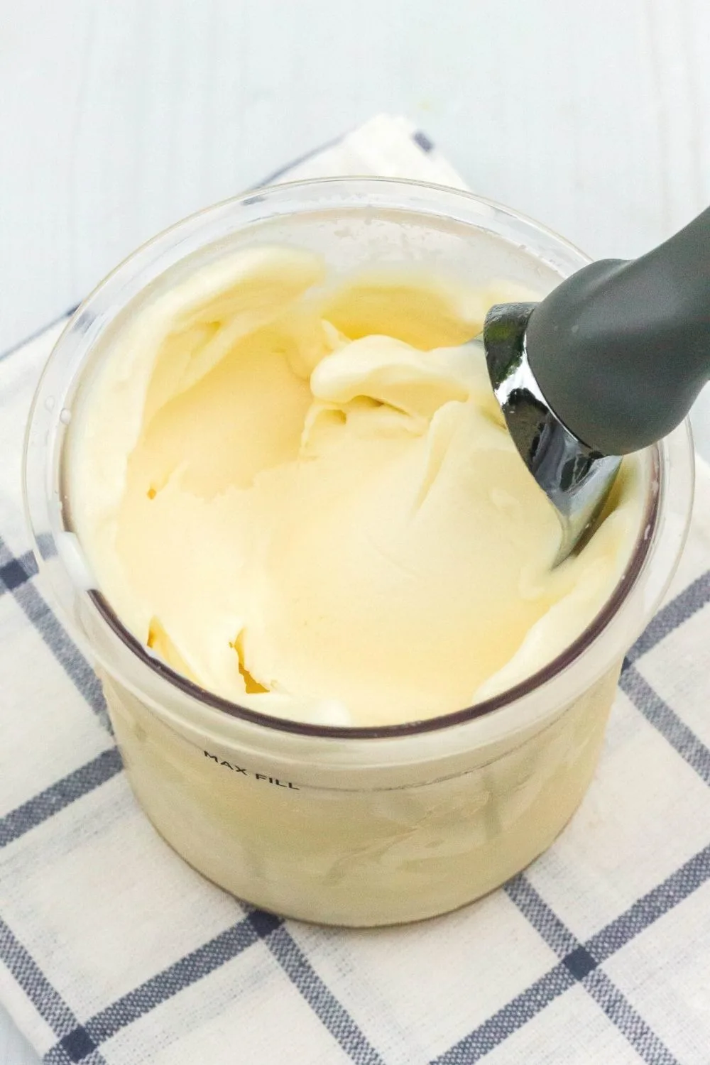 close-up view of a Ninja Creami pint container filled with vanilla ice cream made with cottage cheese. An ice cream scoop is in the ice cream.