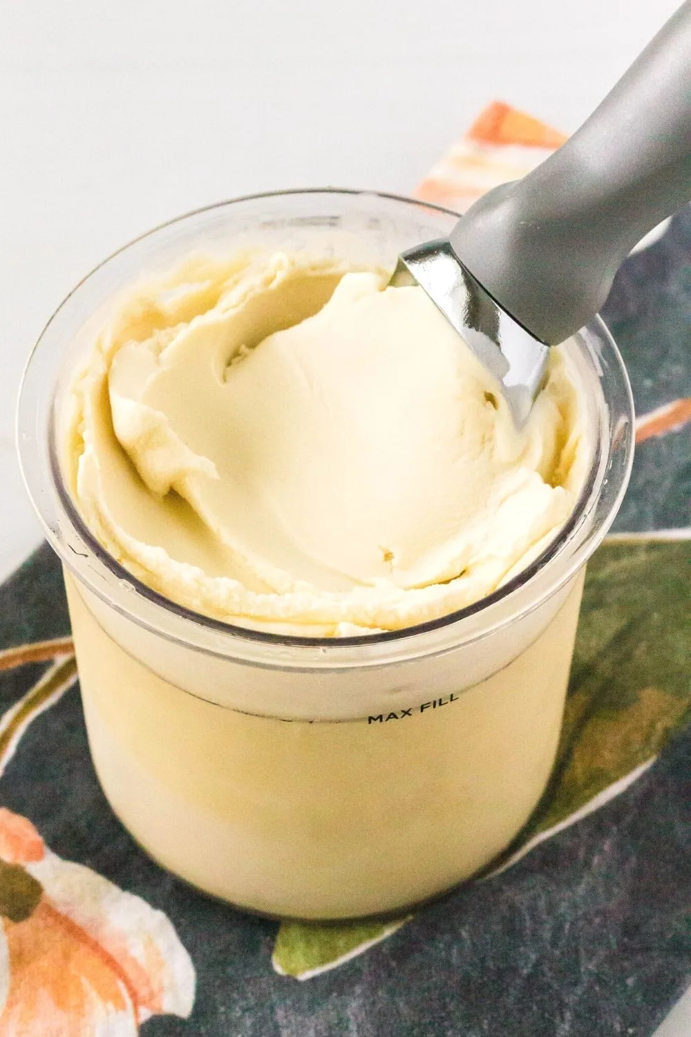 ninja creami pint container filled with dairy-free vanilla ice cream and an ice cream scoop.