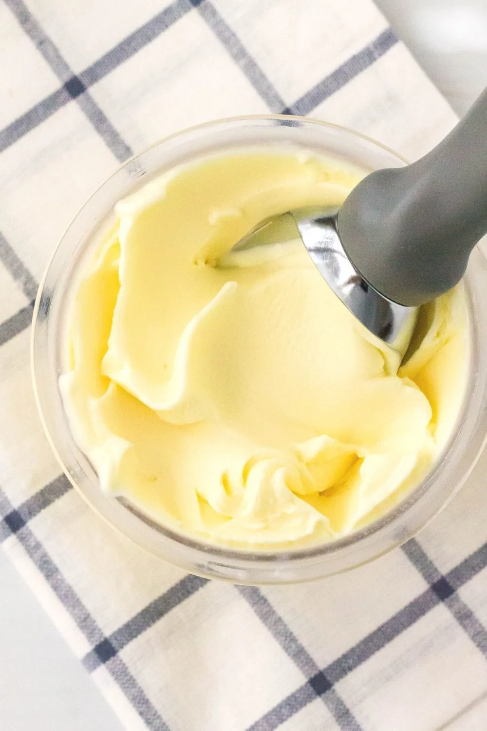 overhead view of a ninja creami pint of lemon ice cream. A scoop is swirling the top of the ice cream, showing its creamy texture.