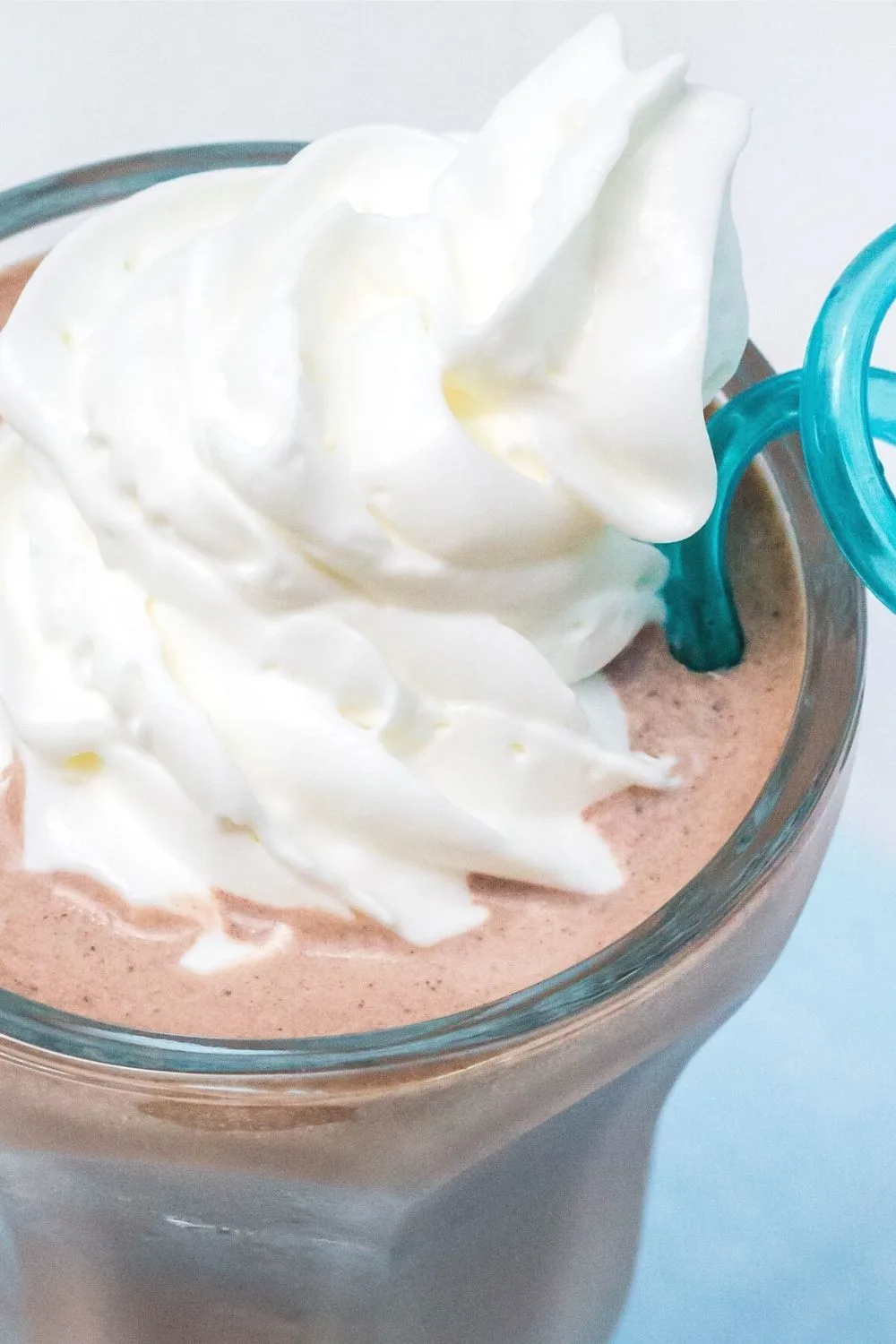 close-up detail view of a Ninja Creami milkshake in chocolate flavor, topped with whipped cream.