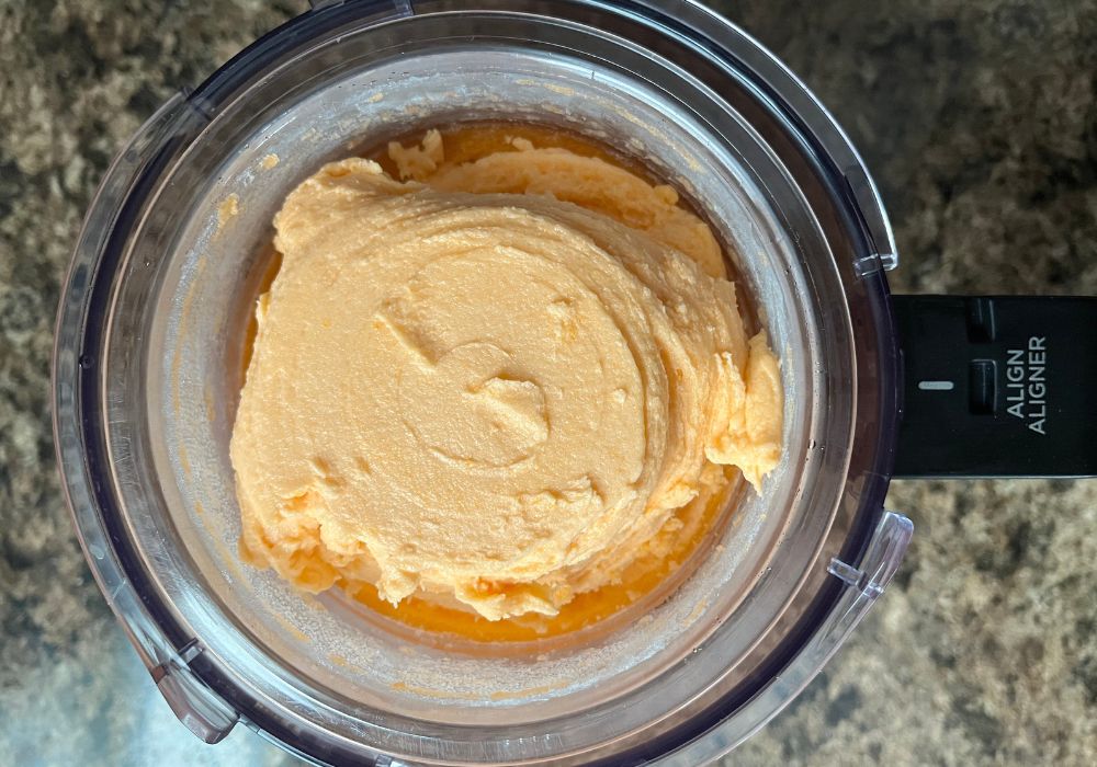 the sides of the ninja creami pint container have been scraped down and the orange sorbet has been re-spun.