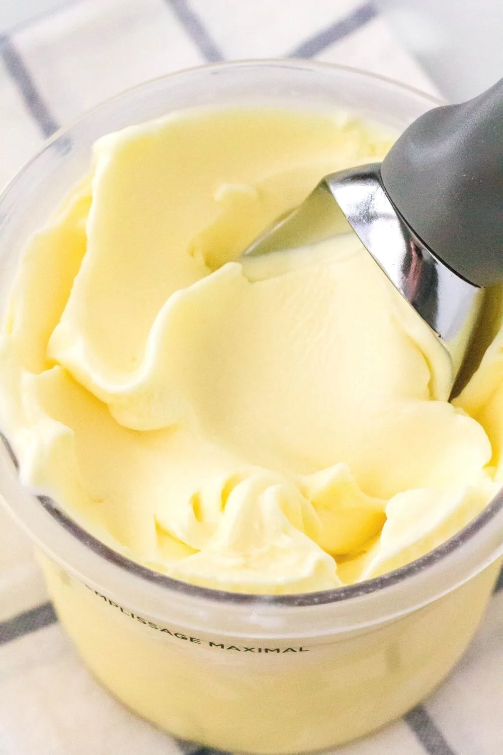 close-up view of a Ninja Creami pint of lemon ice cream with a scoop in it, showing the creamy texture.