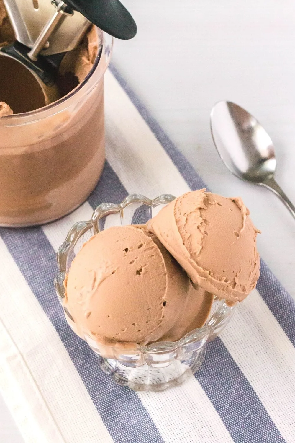 glass dish serving scoops of Ninja Creami dairy free chocolate ice cream. A ninja creami pint of ice cream and a spoon are in the background.