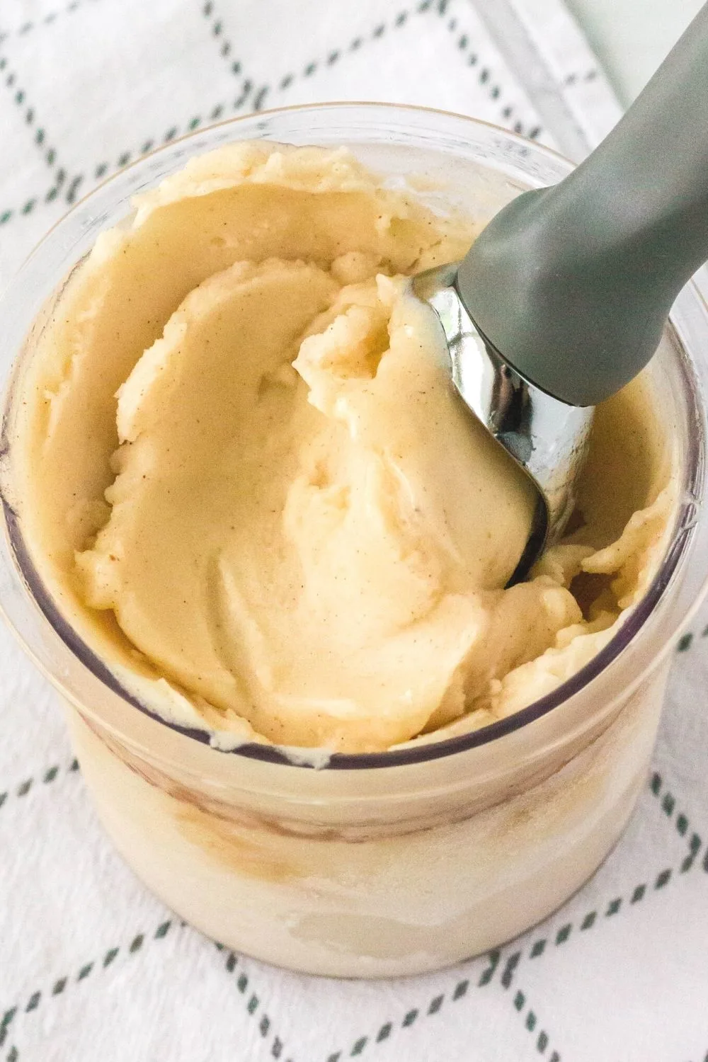 a Ninja Creami pint container filled with pear sorbet made from canned fruit. An ice cream scoop is in the container.