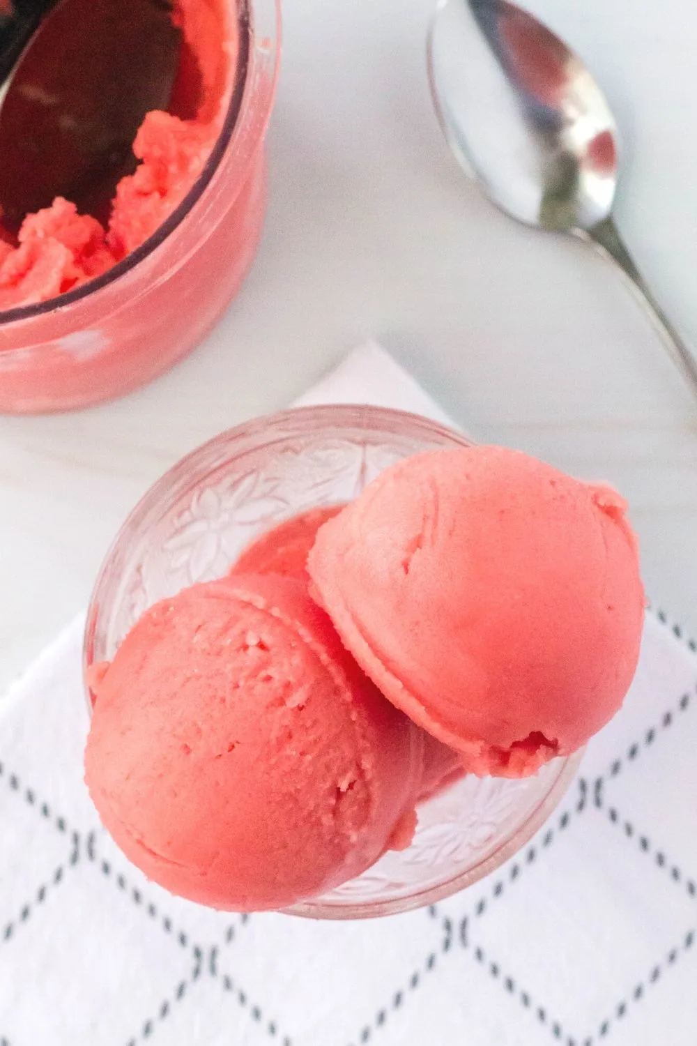 overhead view of a dish serving watermelon sorbet, with the pint container and spoon in the background