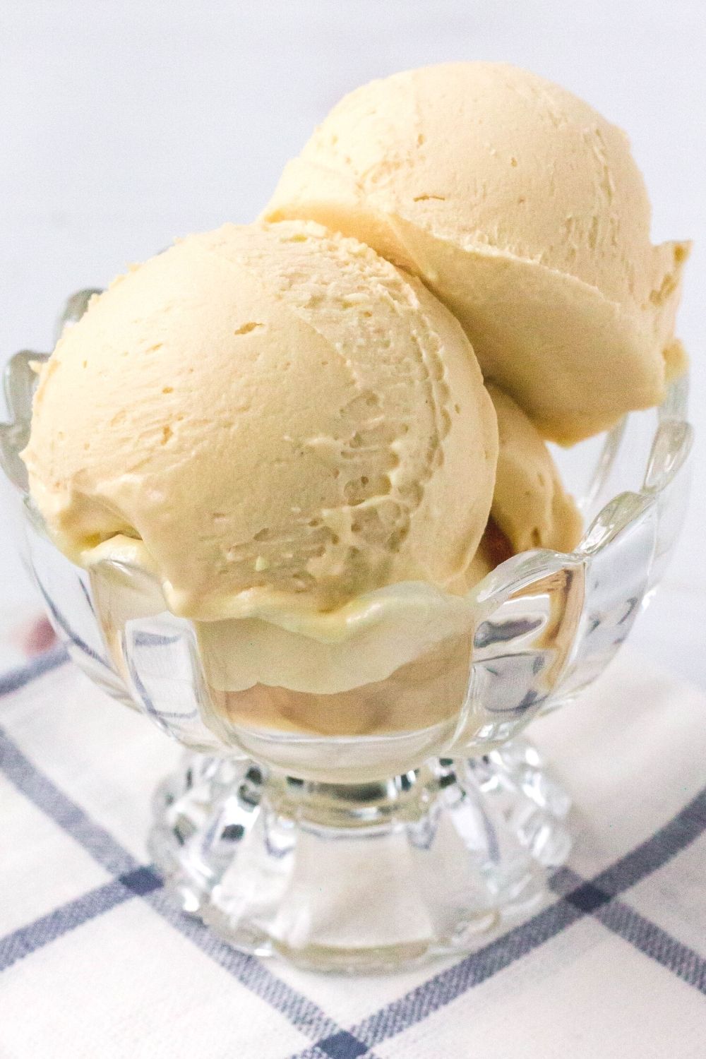 close-up side view of a glass dessert cup serving scoops of peanut butter ice cream made in the Ninja Creami machine.