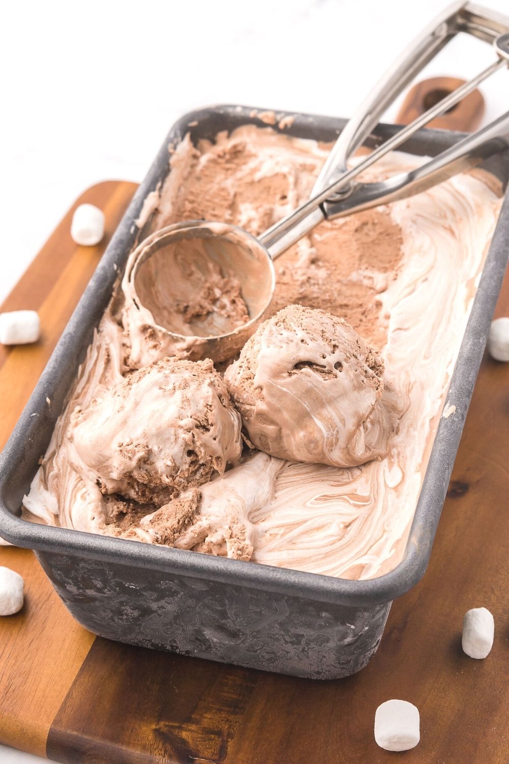 a loaf pan of no churn chocolate marshmallow ice cream with an ice cream scoop in it