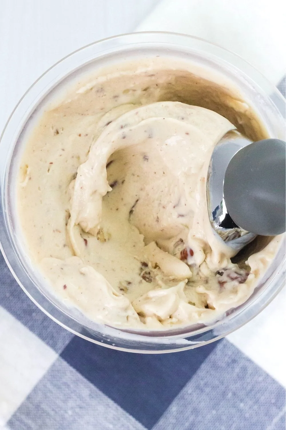 overhead view of banana ice cream in a Ninja Creami pint, with an ice cream scoop in the pint