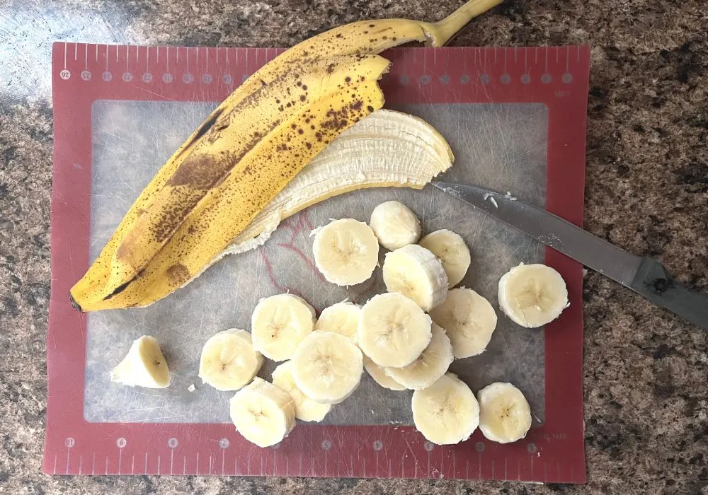 banana slices on a cutting board, with the ripe banana peel next to them.