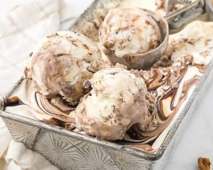 a loaf pan filled with homemade turtle ice cream. An ice cream scoop is in the ice cream.
