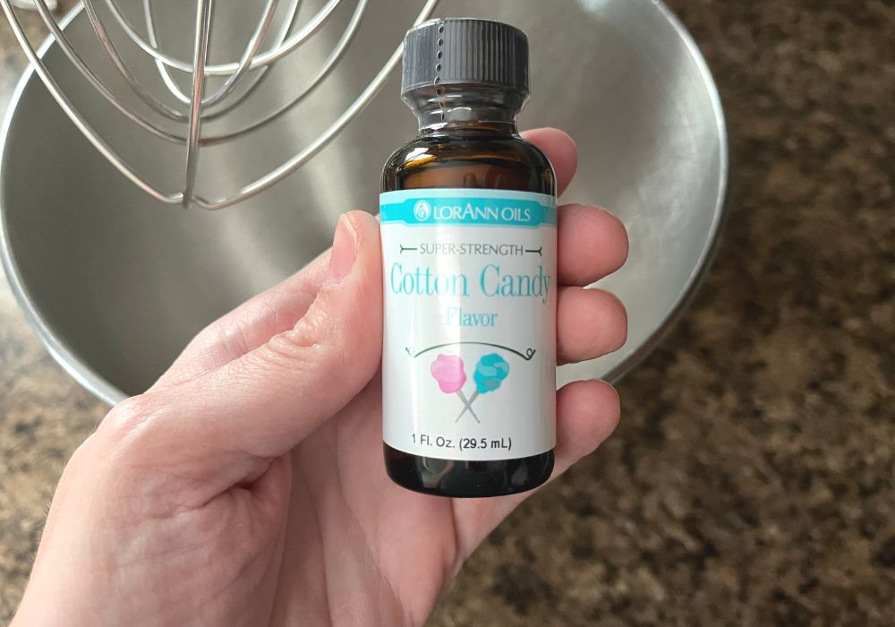 a woman's hand holds a bottle of cotton candy flavor extract