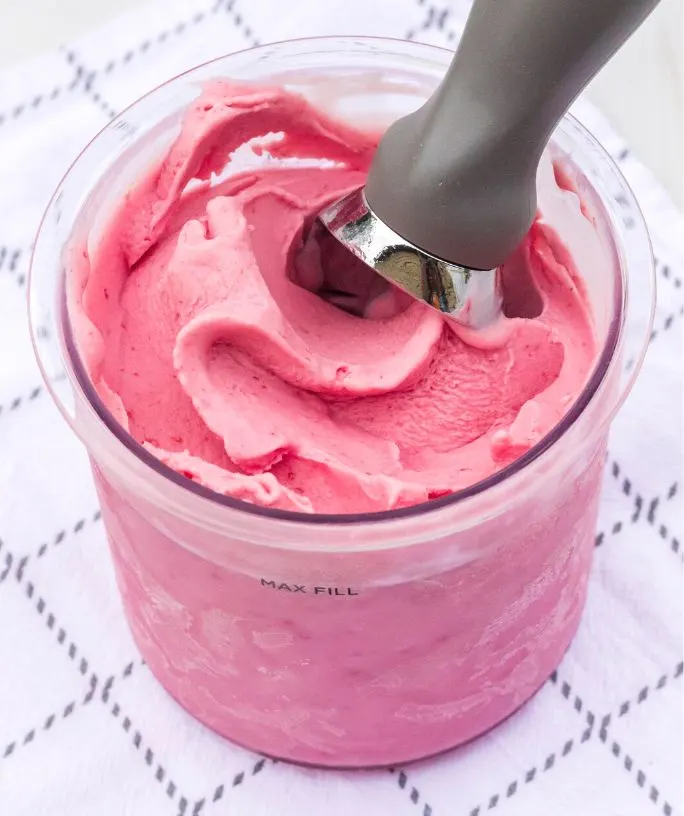 Pint of Ninja Creami cranberry ice cream, with an ice cream scoop in it