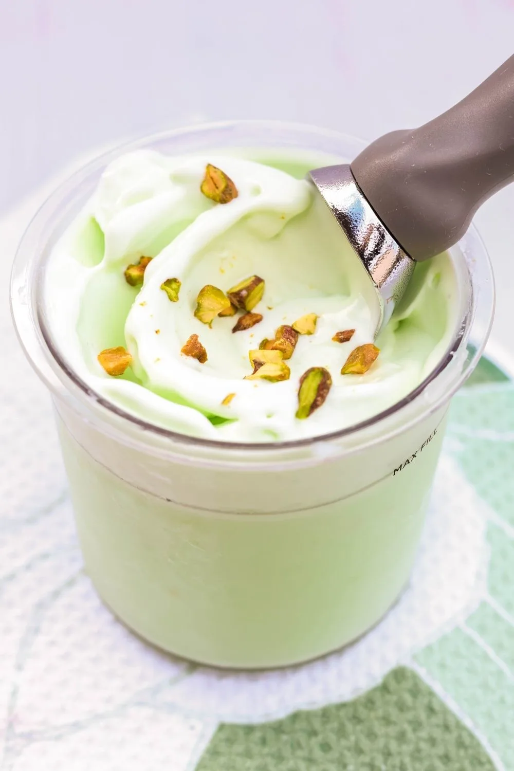 a Ninja Creami pint container of pistachio ice cream, sprinkled with chopped pistachios