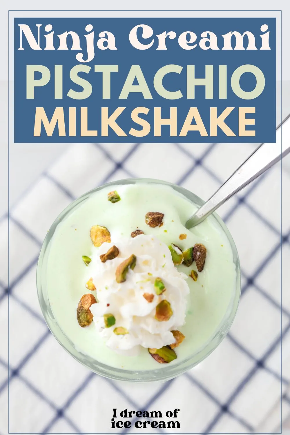 overhead view of Ninja Creami pistachio milkshake served in a glass, topped with whipped cream and chopped pistachios. A spoon is in the glass.
