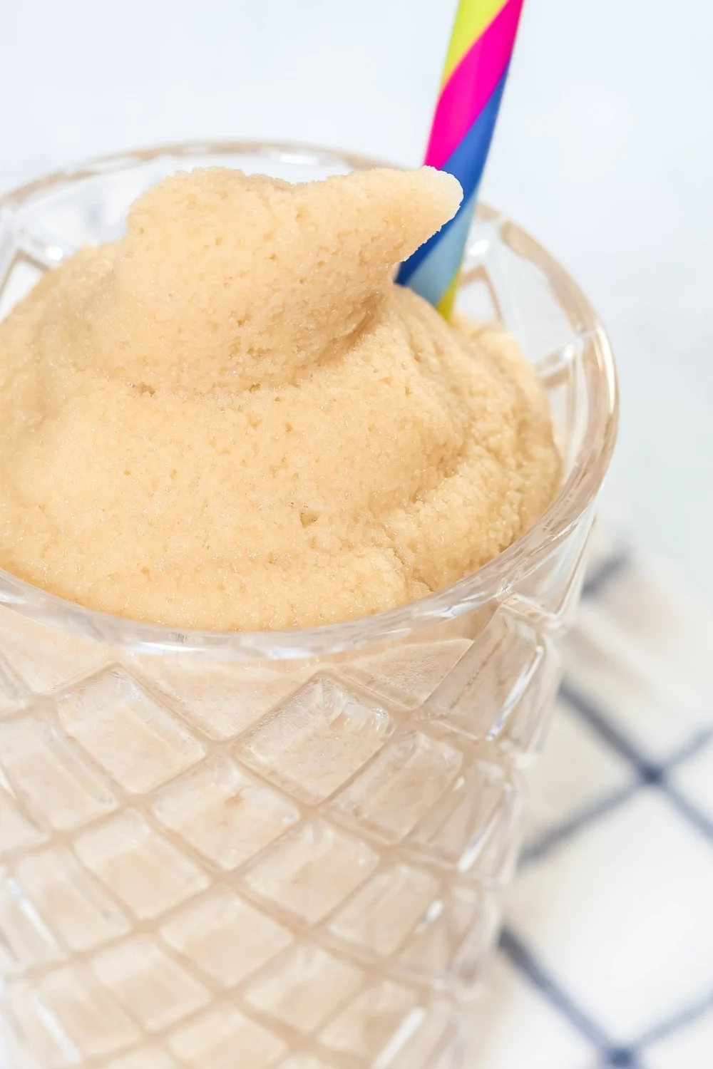 close-up view of a root beer slush that was made in the Ninja Slushi machine, served in a glass with a striped straw.