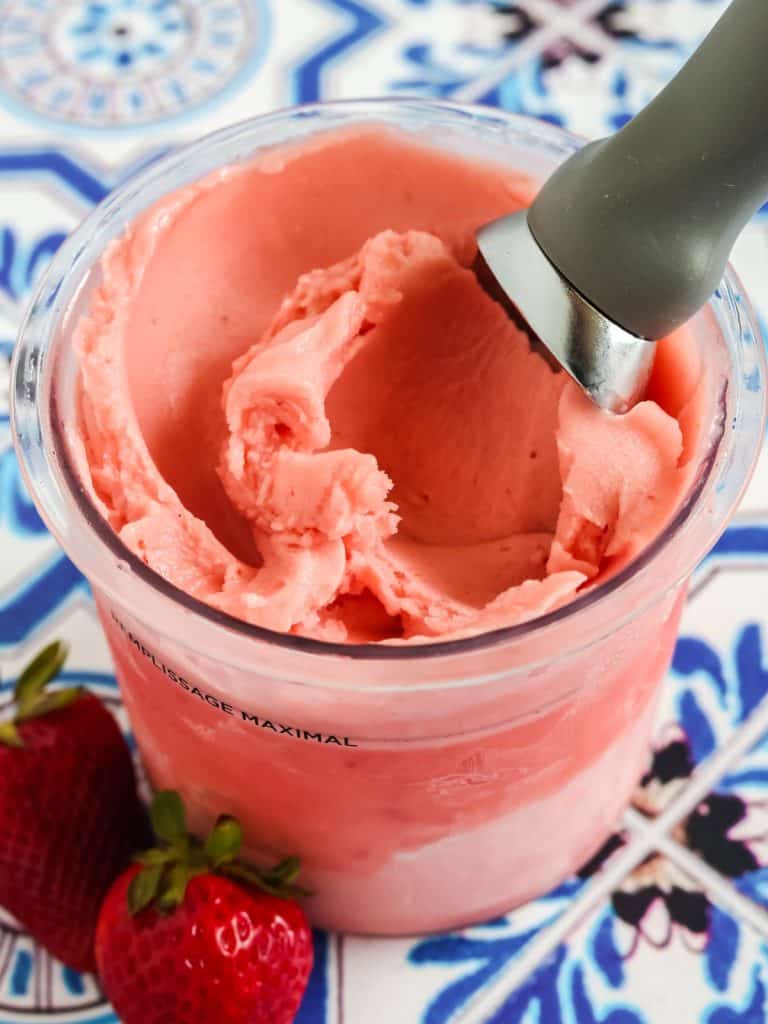 Ninja Creami strawberry Dole Whip in a pint container, with an ice cream scoop in the container.