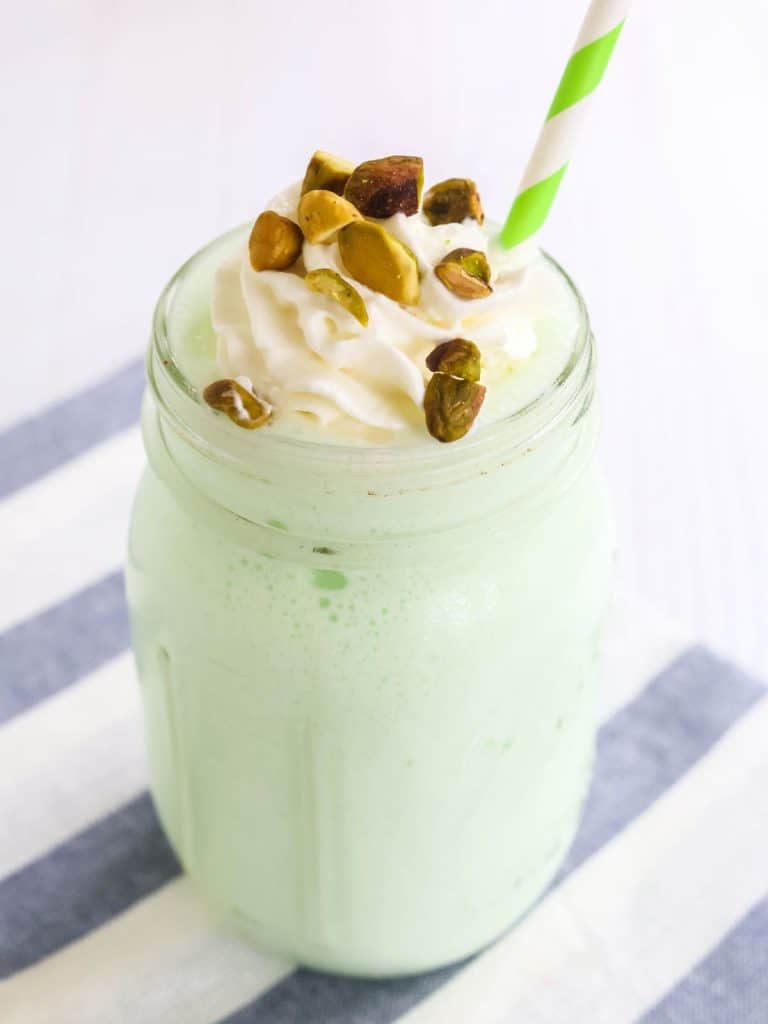 Ninja Slushi pistachio milkshake served in a glass mason jar, topped with chopped pistachio nuts and whipped cream.