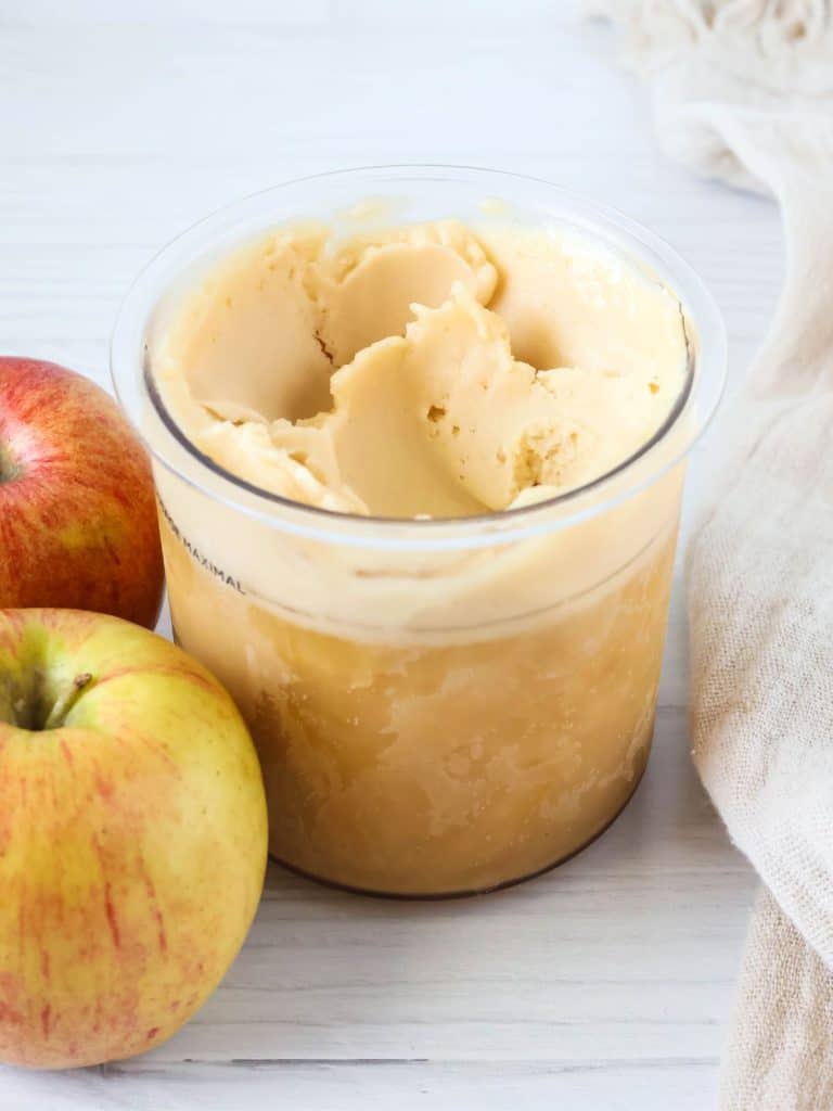 Ninja Creami apple cider sorbet in a pint container, with two apples next to it.