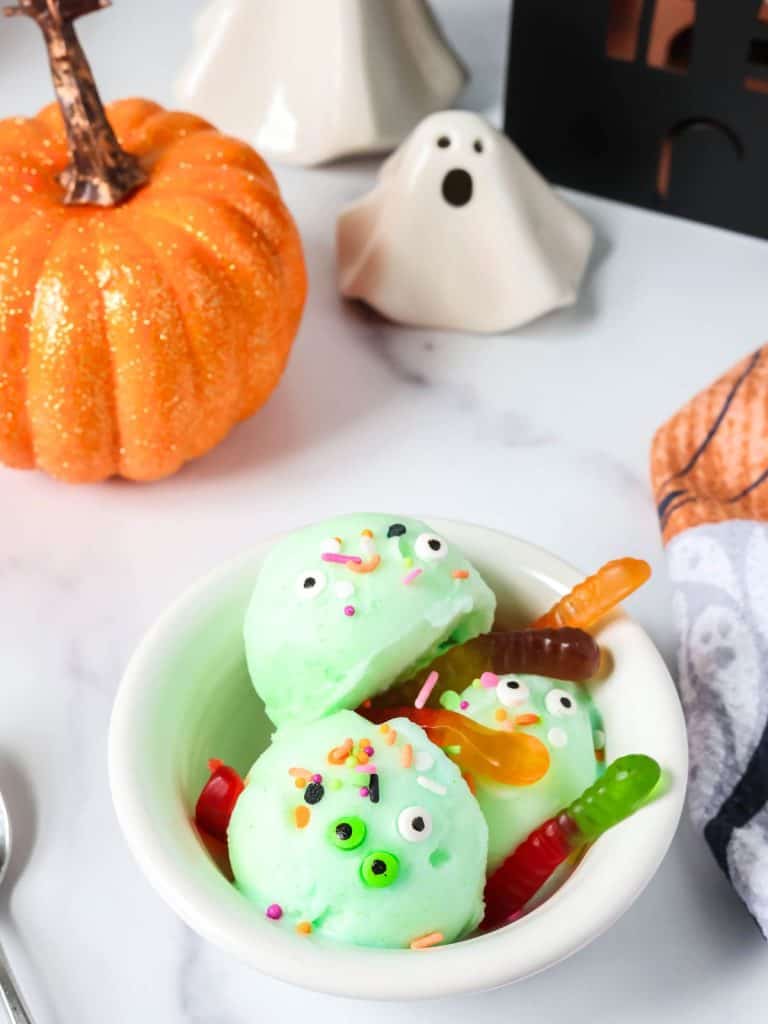 Ninja Creami Halloween sorbet served in a white bowl, garnished with spooky candy eyeballs, gummy worms, and colorful Halloween sprinkles.