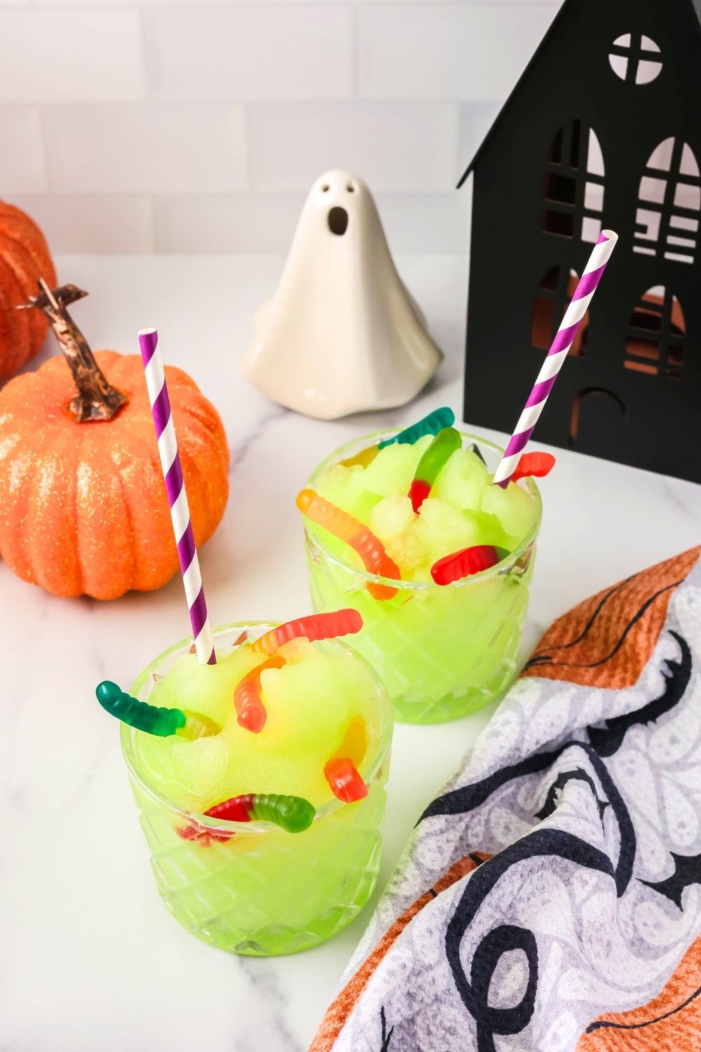 two glasses of Witches' Brew slush, made in the Ninja Slushi machine, served alongside various Halloween decor.