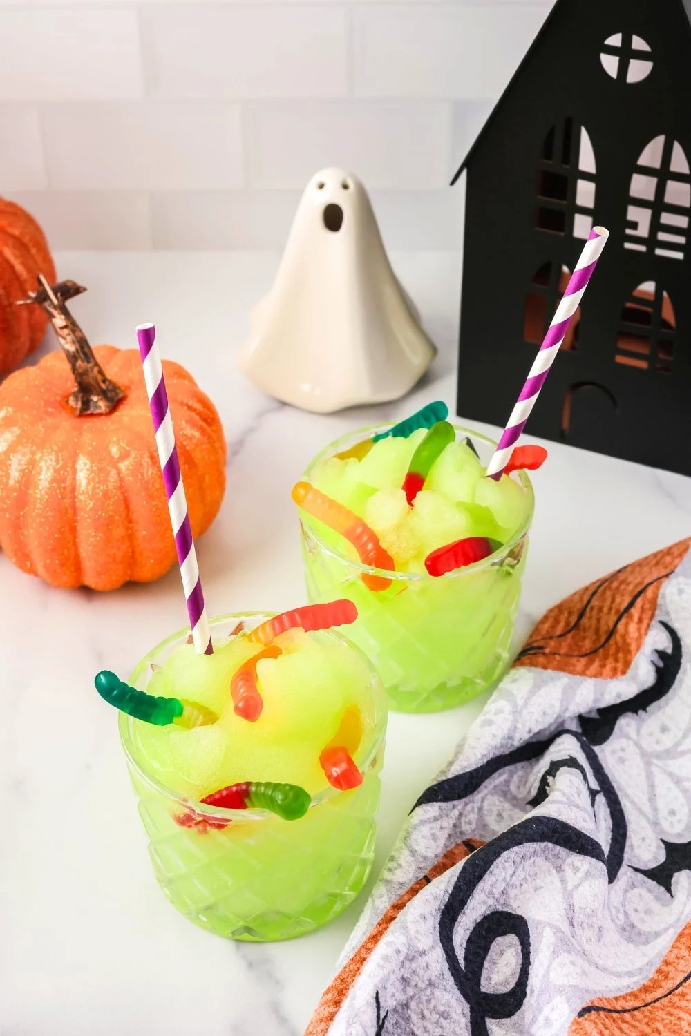 two glasses of Witches' Brew slush, made in the Ninja Slushi machine, served alongside various Halloween decor.