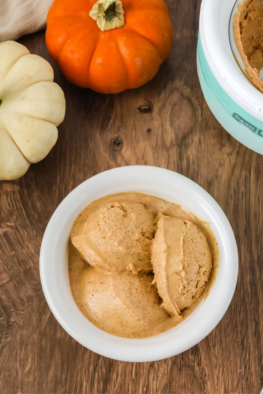 overhead view of a white bowl with scoops of Dash pumpkin soft serve ice cream.