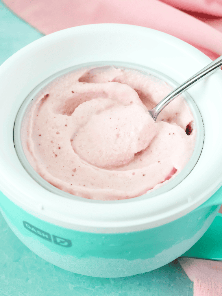Dash My Mug strawberry frozen yogurt with a spoon removing a bite.