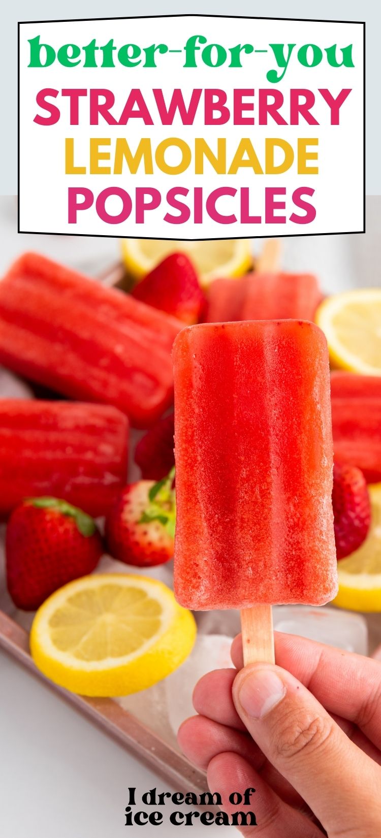 a woman's hand holds a strawberry lemonade popsicle, with more pops in the background.