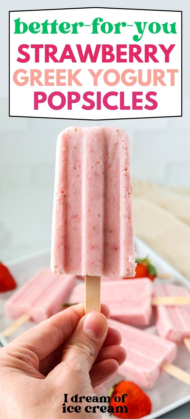 a woman's hand holds a strawberry Greek yogurt popsicle.
