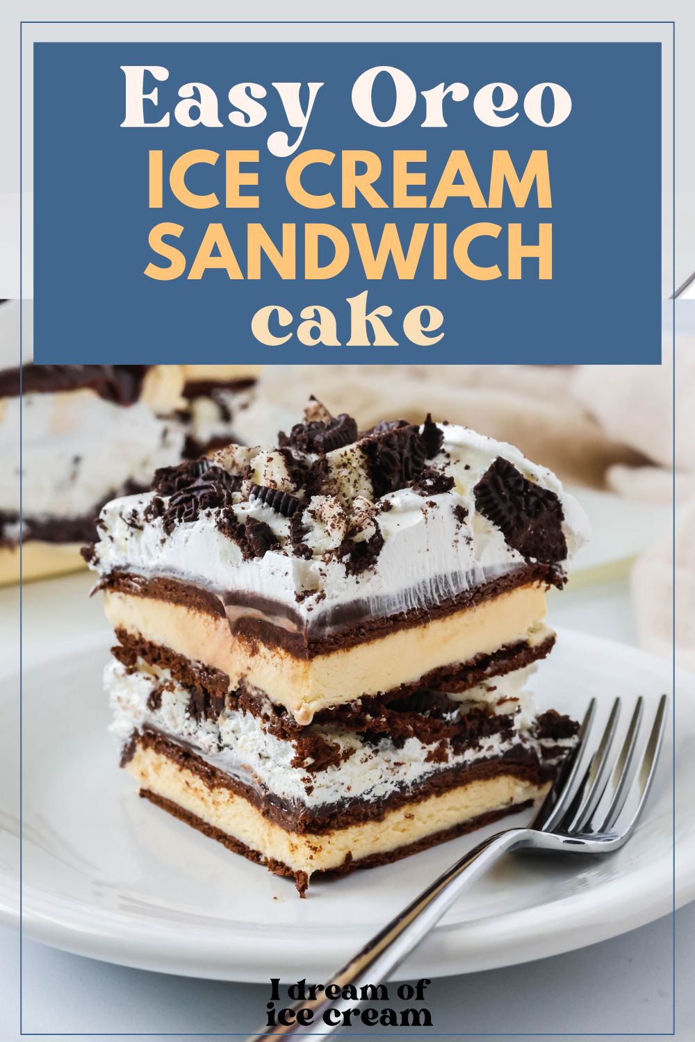 slice of easy ice cream sandwich cake, topped with Oreo cookies, served on a white plate with a fork next to it.