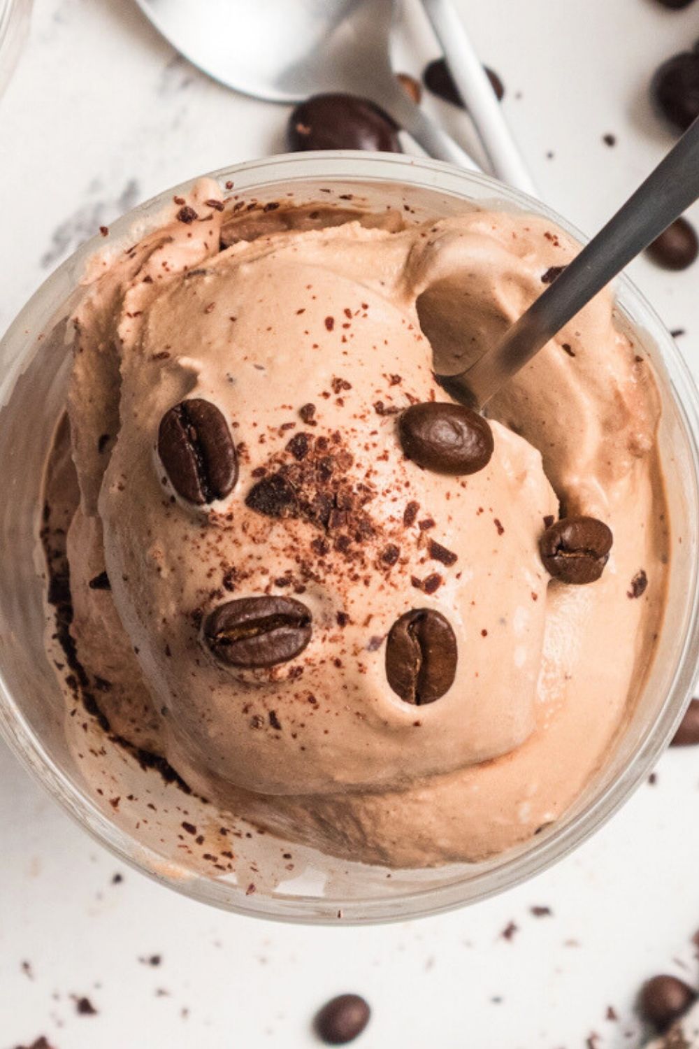 close-up view of mocha ice cream, garnished with coffee beans and chocolate shavings, served in a glass dish.