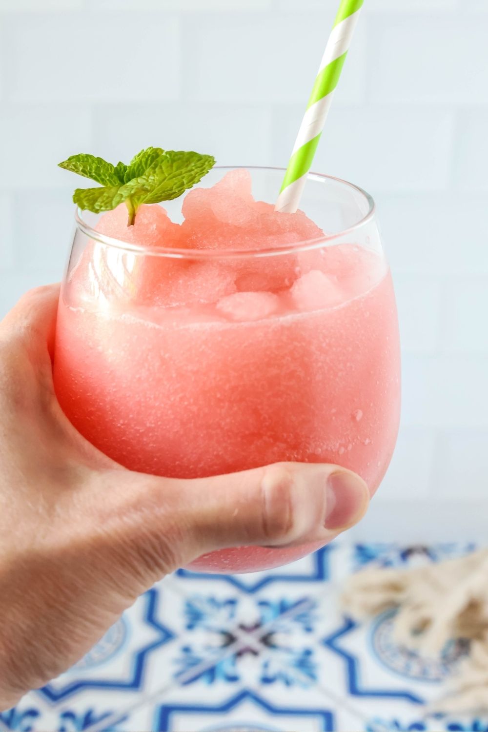 A woman's hand holds a glass of easy watermelon lime slushie.