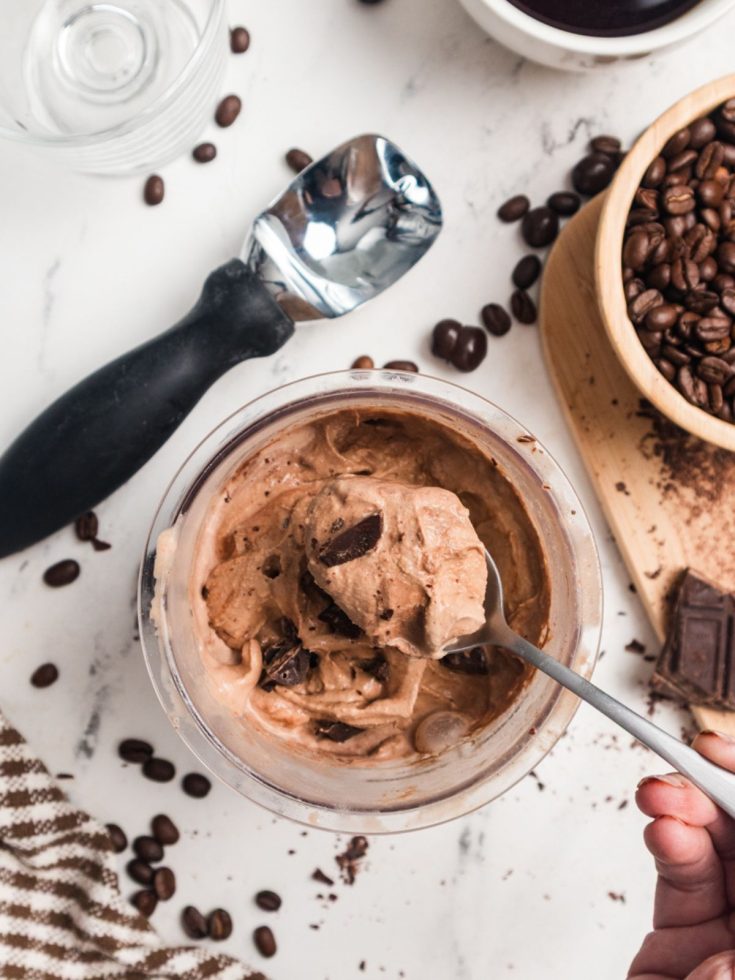 a spoon lifts out a bite of Ninja Creami mocha ice cream from a pint container.