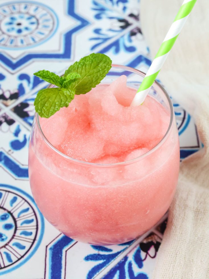 Ninja Slushi Watermelon Limeade Slush served in a glass with a straw and sprig of mint.